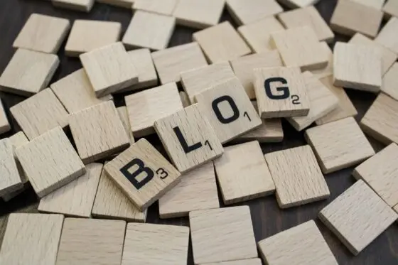 Jetons de Scrabble en bois éparpillés, certains alignés formant le mot « blog »